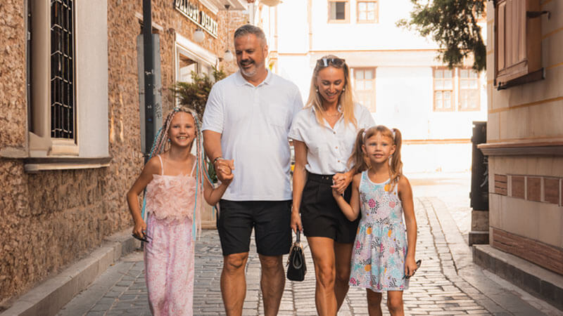 Rodina s mužem, ženou a dvěma dcerami na procházce po městě během západu slunce.